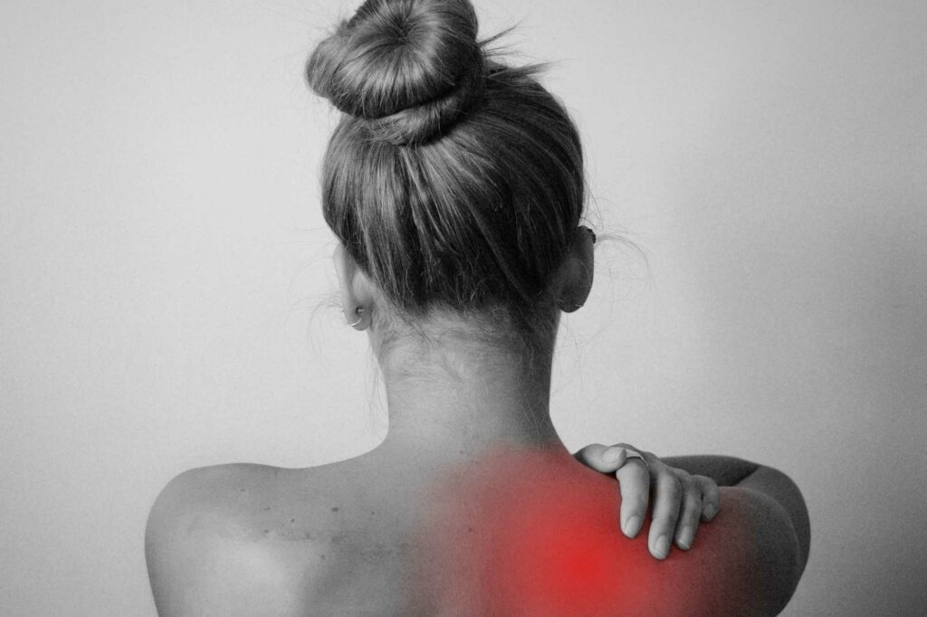 Rückenansicht einer Frau von hinten. Im Schulterbereich symbolisiert eine rote Einfärbung Schmerzen