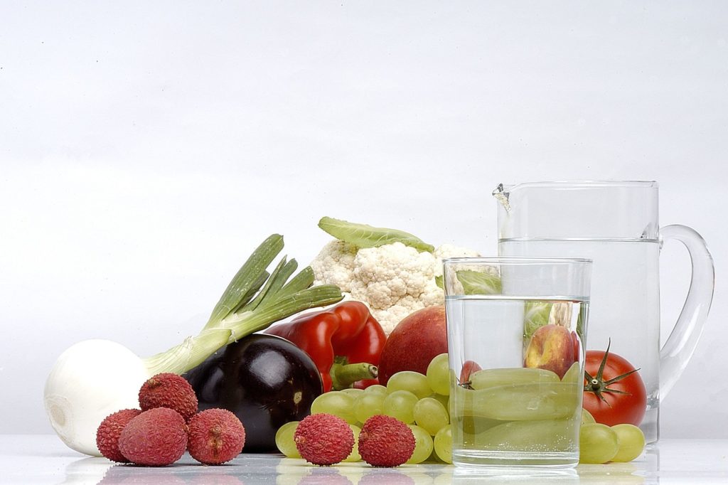 Stillleben aus Obst und Gemüse sowie einem Glas und einem Krug mit Wasser